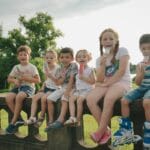 Dzieci jedzą kolorowe lody na patyku w słoneczny, letni dzień