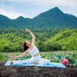 Najlepsze agroturystyki z sauną i zajęciami jogi na Mazurach, Podlasiu i w Beskidach Kobieta ćwicząca jogę na tle gór wśród zielonych pól lotosu