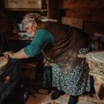 Starsza kobieta piecze tradycyjny chleb w wiejskiej kuchni