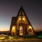Oświetlona nocą górska chatka A-frame z widokiem na szczyty