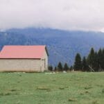 Dom agroturystyczny w górach otoczony zielenią pod pochmurnym niebem