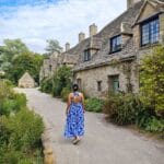Kobieta w niebieskiej sukience idąca przez letnią wieś w Cotswolds