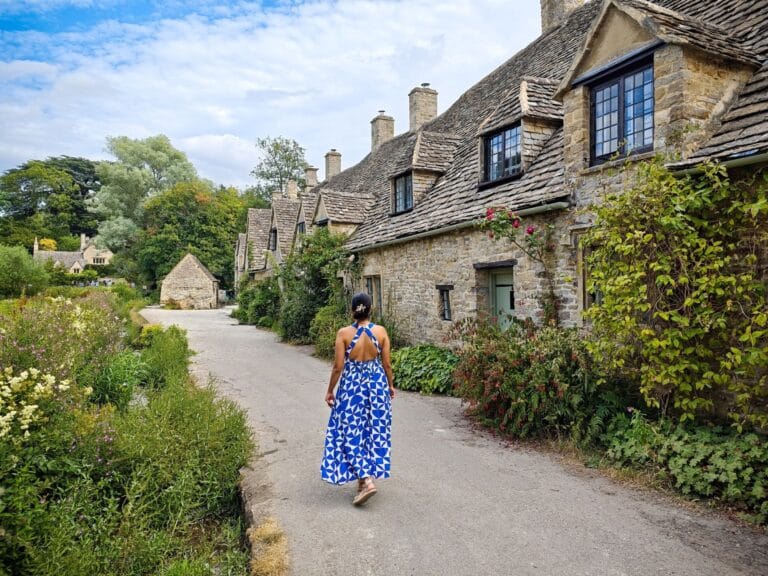 Kobieta w niebieskiej sukience idąca przez letnią wieś w Cotswolds